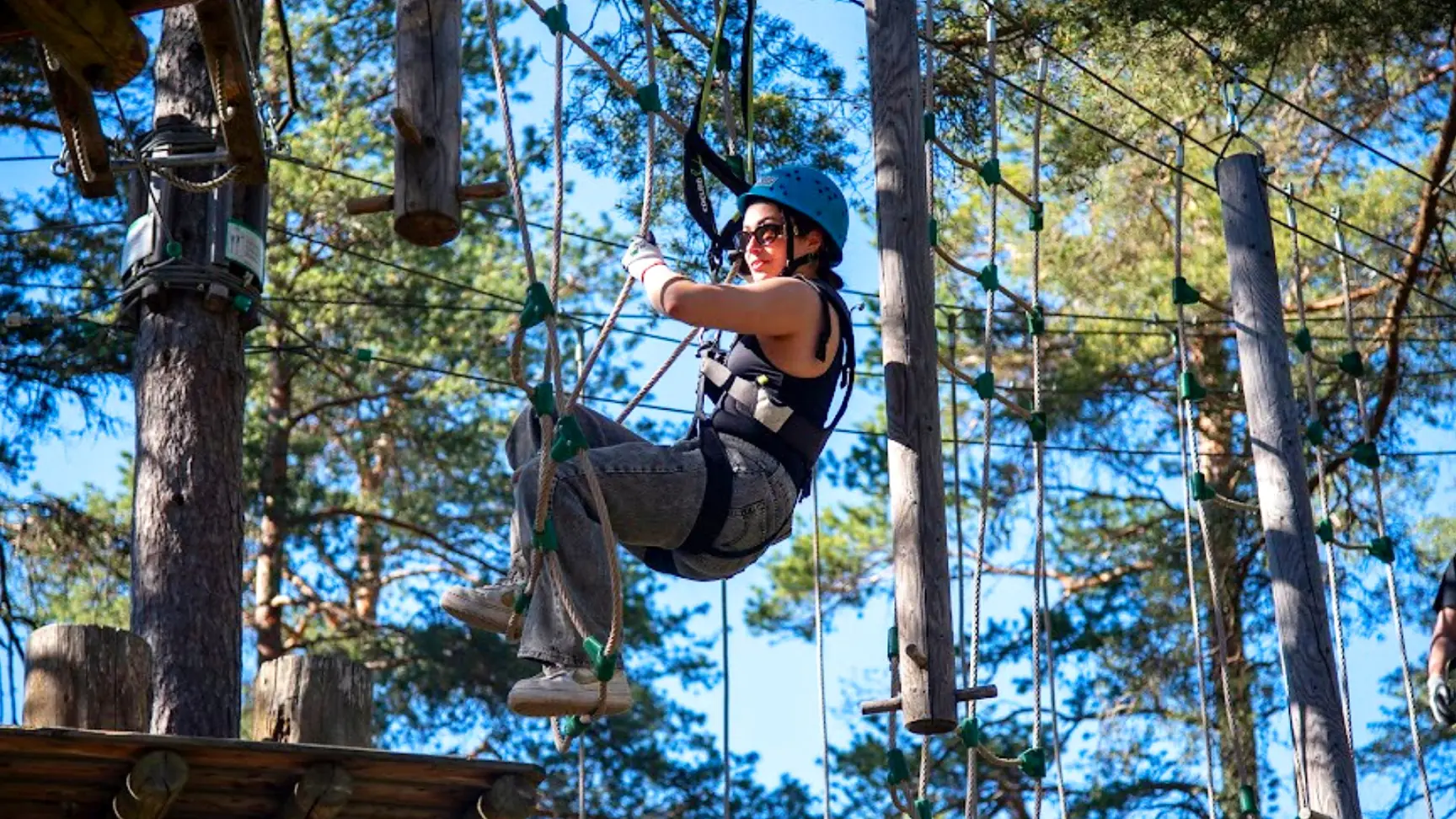 Kiipeilijä köysiradalla auringonvalossa Korkeen latvoissa